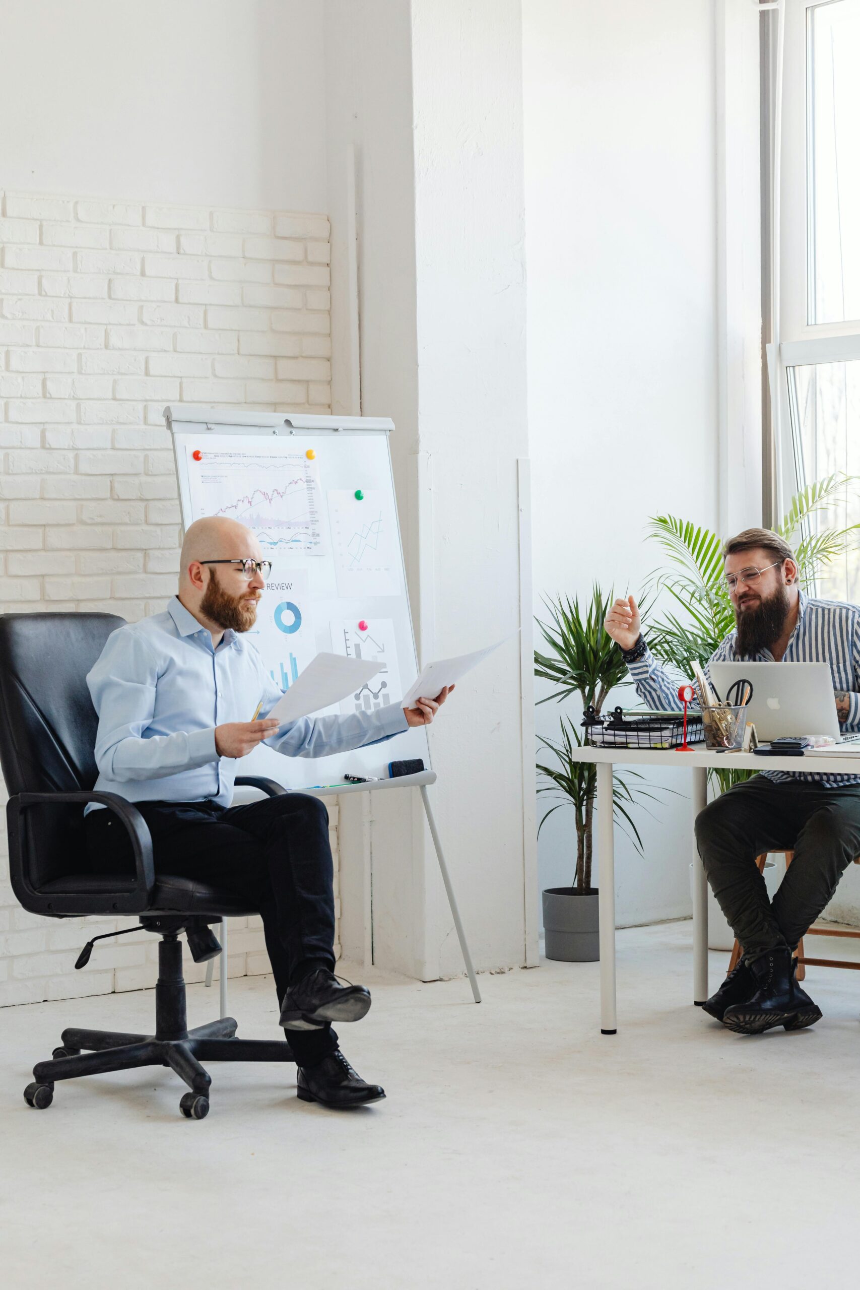 Two businessmen discussing documents during a meeting in a bright office space.